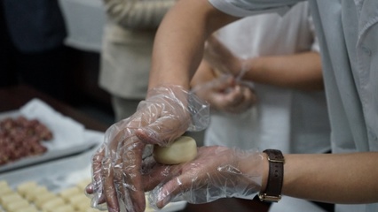 按扁面团、加入馅料、揉搓成型,糕点师傅现场制作手工月饼。人民网记者 栗翘楚摄
